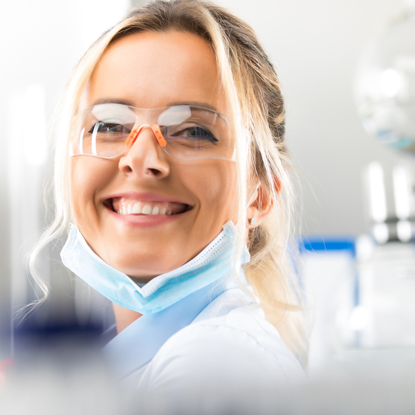 Portrait of happy young attractive smiling woman scientist with protective eyeglasses in the scientific chemical laboratory